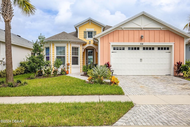 318 Good Life Way, Daytona Beach, FL 32124 - traditional-style house with decorative driveway, board and batten siding, an attached garage, and a front lawn