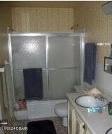 full bathroom with vanity, toilet, and enclosed tub / shower combo