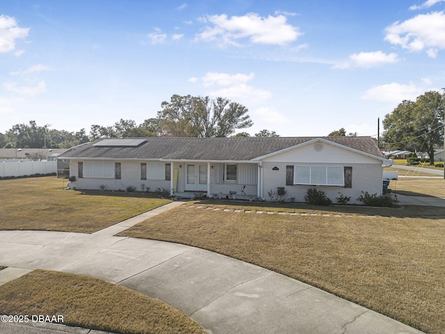 ranch-style house featuring a front yard and solar panels