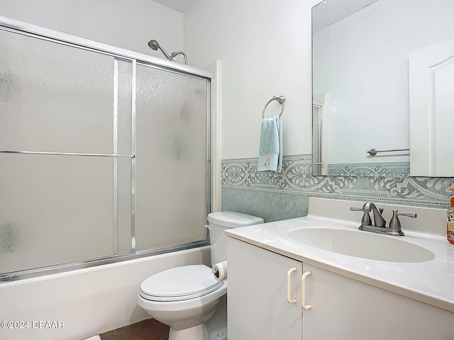 full bathroom with toilet, combined bath / shower with glass door, vanity, and backsplash