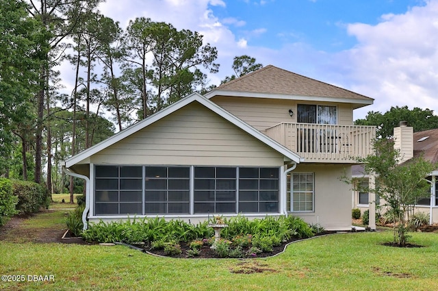 back of property featuring a lawn, a balcony, and a sunroom