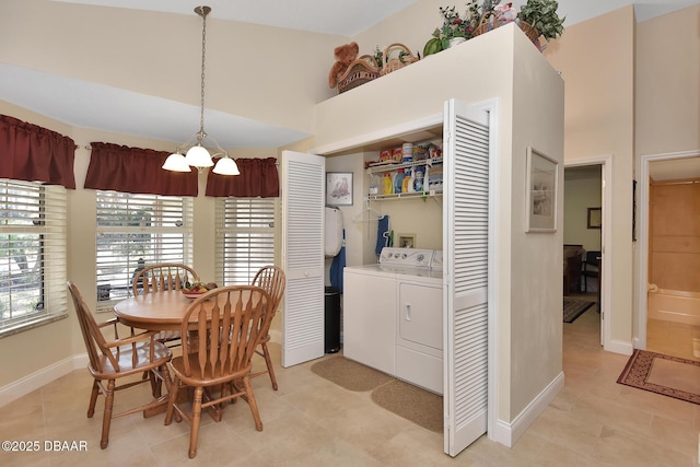 dining area with washing machine and dryer, a chandelier, light tile patterned flooring, and high vaulted ceiling