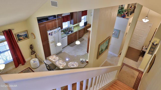 interior space with white appliances, vaulted ceiling, kitchen peninsula, and hanging light fixtures