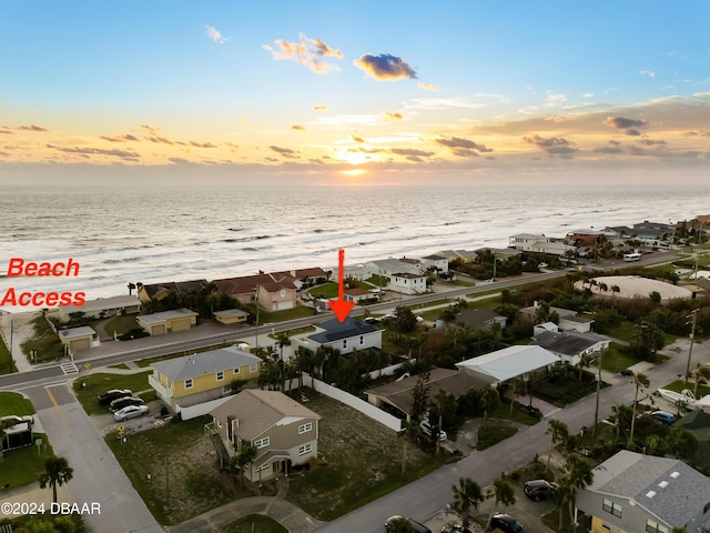 aerial view at dusk featuring a water view