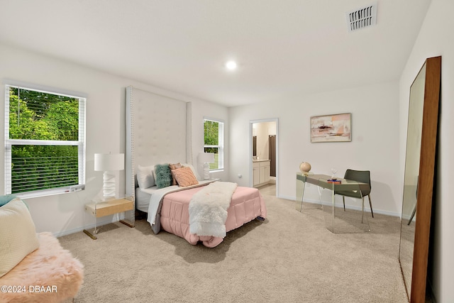 bedroom with ensuite bath and light carpet