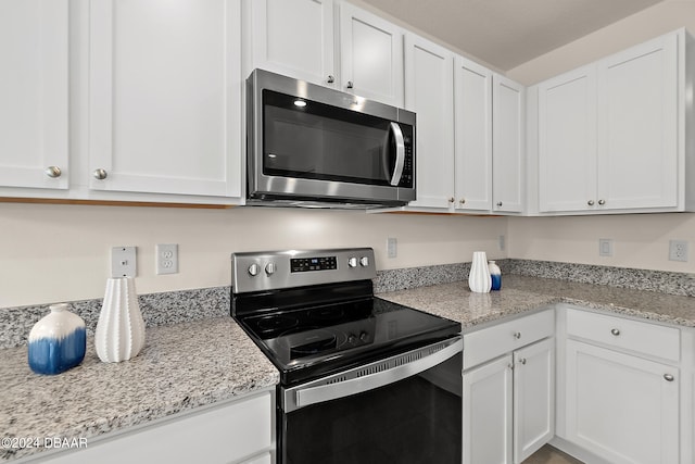 kitchen with white cabinets, appliances with stainless steel finishes, and light stone counters