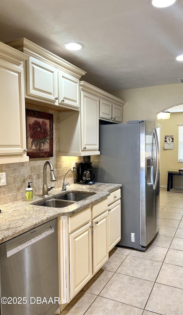 kitchen featuring stainless steel appliances, cream cabinets, sink, and light tile patterned floors