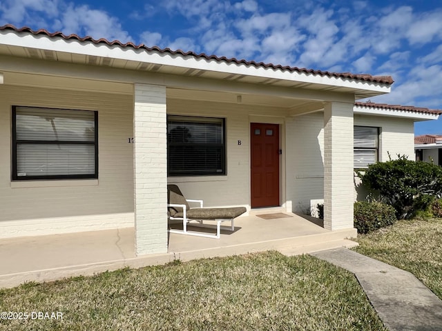 doorway to property featuring a yard and covered porch