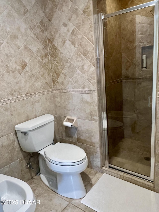 bathroom featuring a bidet, tile patterned flooring, tile walls, toilet, and walk in shower