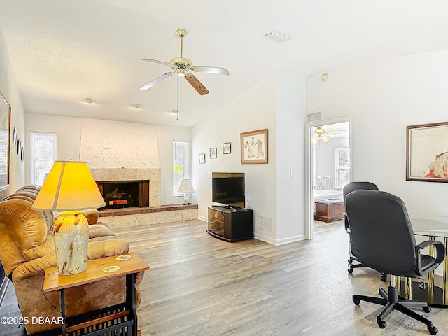 living room featuring lofted ceiling, ceiling fan, light wood-type flooring, and visible vents