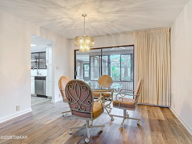 dining space featuring baseboards, a textured ceiling, a chandelier, and wood finished floors