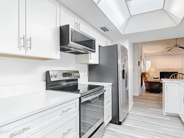 kitchen with light wood-style flooring, stainless steel appliances, visible vents, white cabinets, and open floor plan