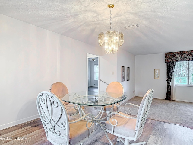 dining space with light wood-style floors, a textured ceiling, and baseboards