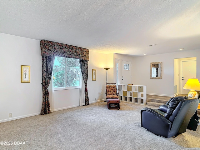 living area with light carpet, a textured ceiling, visible vents, and baseboards