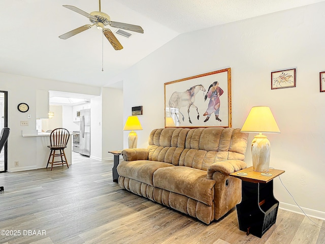 living room with lofted ceiling, light wood-style flooring, visible vents, baseboards, and a ceiling fan