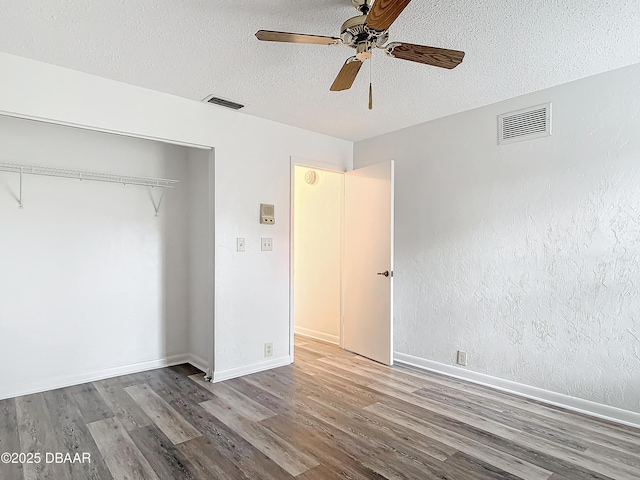 unfurnished bedroom with visible vents, light wood-style flooring, and a textured ceiling