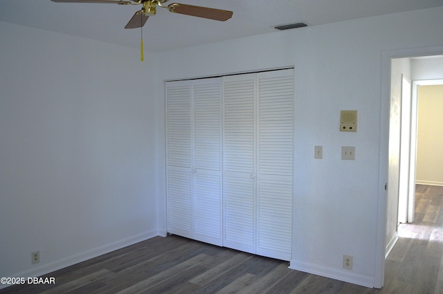 unfurnished bedroom featuring baseboards, visible vents, ceiling fan, dark wood-style flooring, and a closet