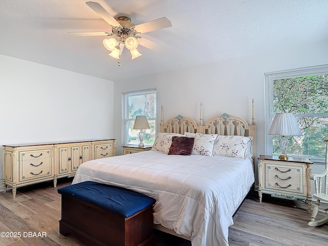 bedroom with light wood-style floors, a ceiling fan, and a textured ceiling