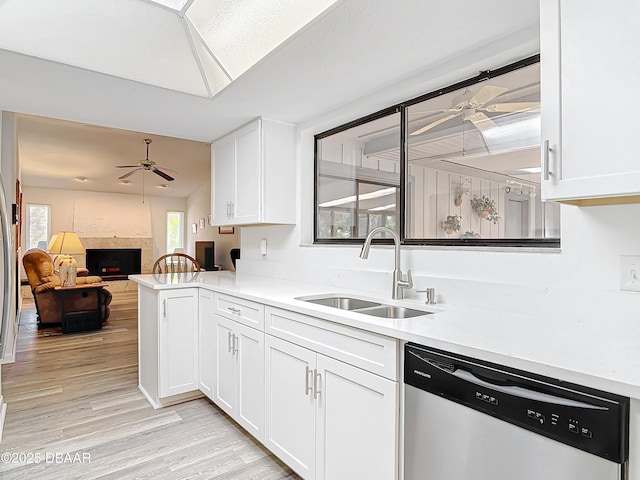 kitchen featuring a sink, a ceiling fan, open floor plan, light countertops, and stainless steel dishwasher