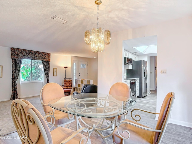 dining room with baseboards, a textured ceiling, visible vents, and an inviting chandelier