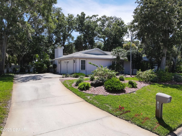 view of front of home featuring a garage, concrete driveway, a front lawn, and a chimney