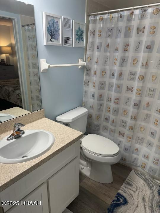 bathroom featuring a shower with curtain, toilet, wood finished floors, and vanity