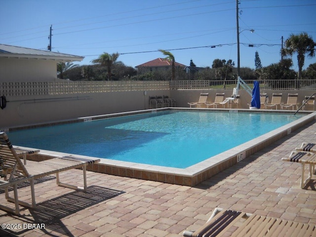 community pool with a patio and fence