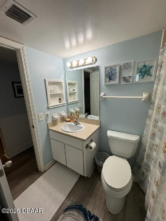 full bath featuring visible vents, toilet, vanity, and wood finished floors