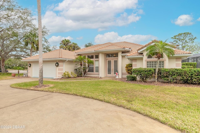 mediterranean / spanish-style home featuring a front yard, french doors, and a garage