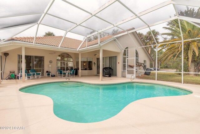 view of swimming pool with ceiling fan, a patio area, and a lanai