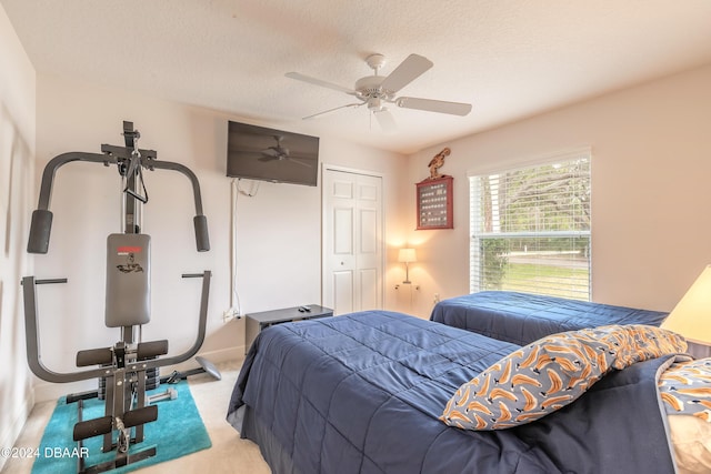 carpeted bedroom with ceiling fan, a closet, and a textured ceiling