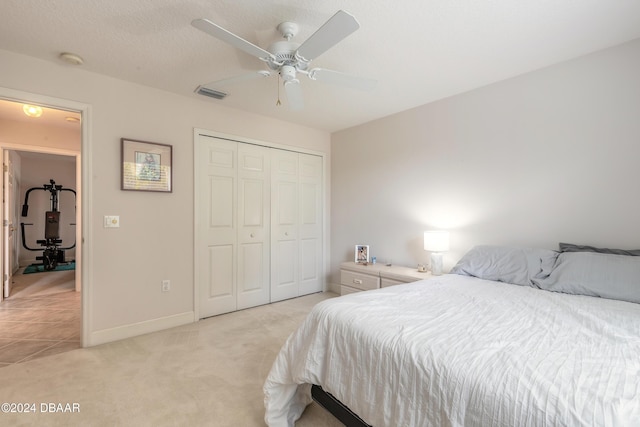 carpeted bedroom with a textured ceiling, a closet, and ceiling fan