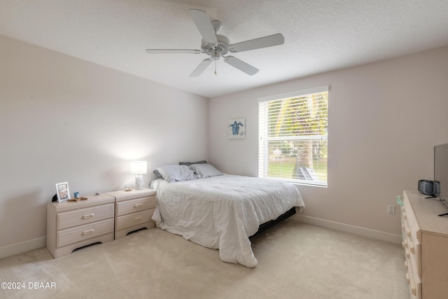 bedroom with a textured ceiling, ceiling fan, and light carpet