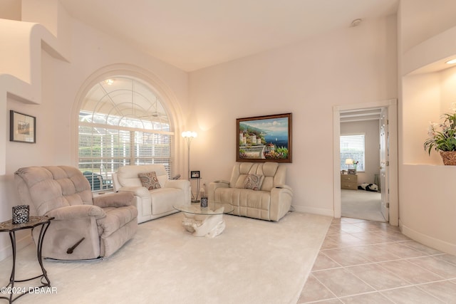 living room with a towering ceiling, a healthy amount of sunlight, and light tile patterned flooring