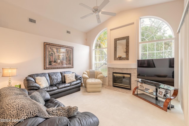 living room featuring ceiling fan, a tiled fireplace, carpet floors, and vaulted ceiling