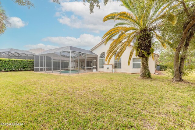 rear view of house featuring glass enclosure and a lawn