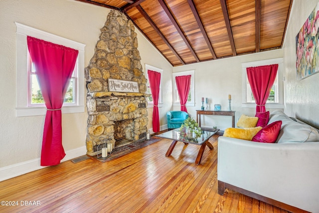 living room featuring a stone fireplace, lofted ceiling with beams, wood-type flooring, and wooden ceiling