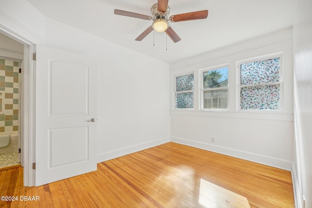 spare room featuring baseboards, light wood finished floors, and ceiling fan