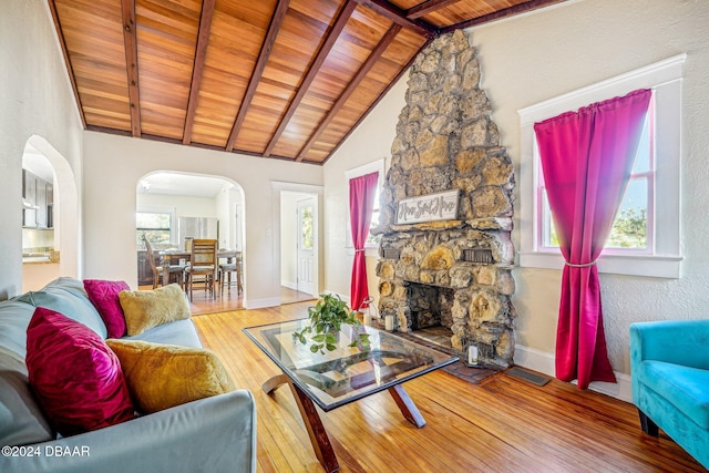 living room featuring hardwood / wood-style flooring, beam ceiling, high vaulted ceiling, a fireplace, and wood ceiling