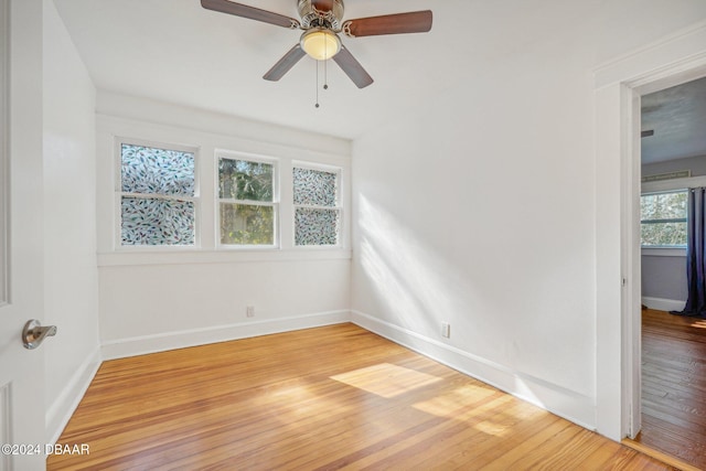 spare room with baseboards, light wood finished floors, and ceiling fan