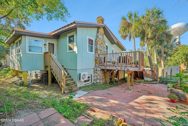 rear view of property with a wooden deck, a patio, a chimney, and stairway