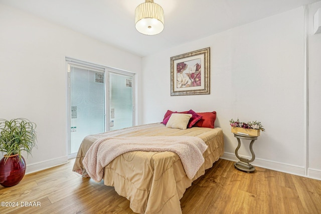 bedroom with access to exterior, light wood-style floors, and baseboards