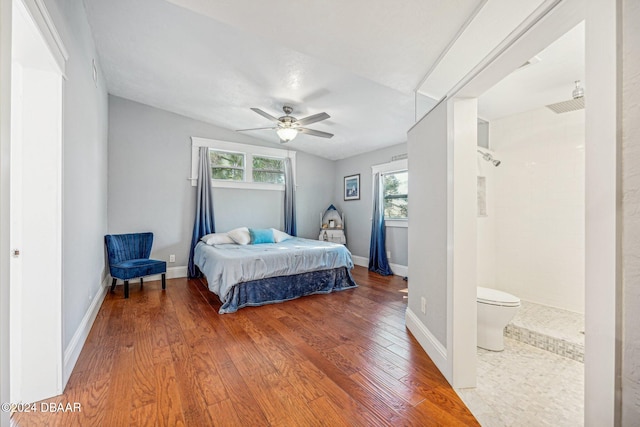 bedroom featuring ceiling fan, baseboards, multiple windows, and wood finished floors