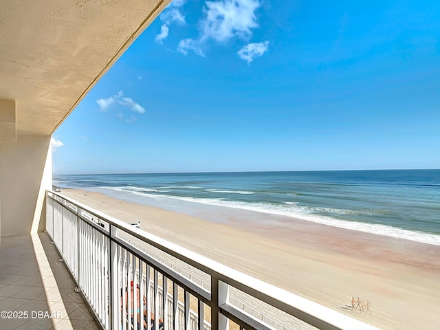 balcony with a water view and a view of the beach