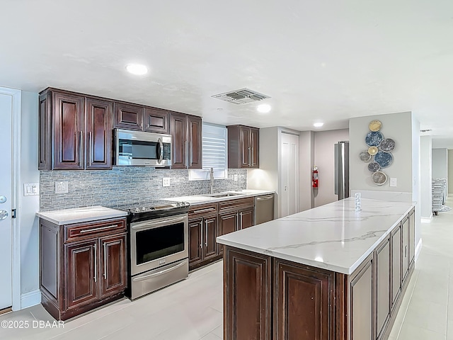 3333 S Atlantic Ave Unit 505, Daytona Beach, FL 32118 - kitchen with stainless steel appliances, a sink, tasteful backsplash, light stone counters, and dark brown cabinets