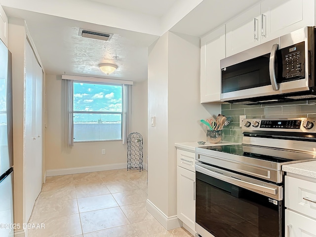 3333 S Atlantic Ave Unit 505, Daytona Beach, FL 32118 - kitchen with appliances with stainless steel finishes, tasteful backsplash, light countertops, white cabinets, and baseboards