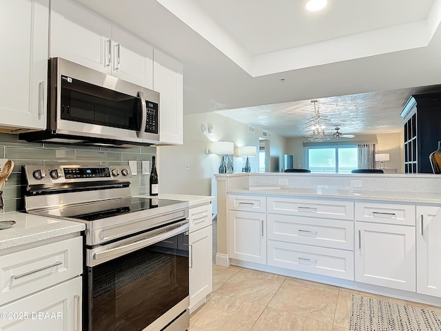 3333 S Atlantic Ave Unit 505, Daytona Beach, FL 32118 - kitchen with appliances with stainless steel finishes, backsplash, white cabinetry, a raised ceiling, and light stone counters