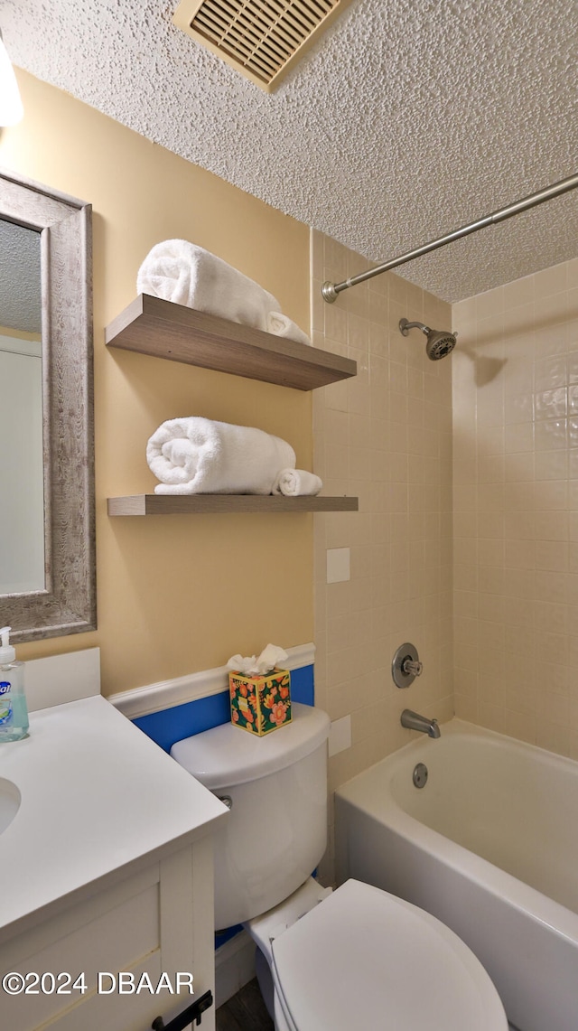 full bathroom with vanity, tiled shower / bath combo, and toilet