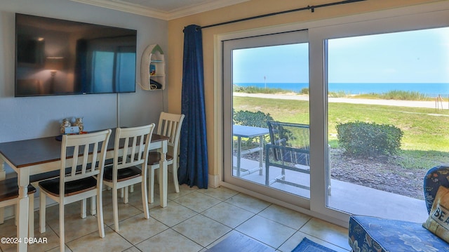 dining area featuring a water view, light tile patterned floors, and crown molding