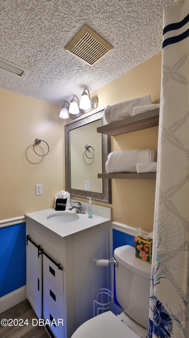 bathroom with toilet, vanity, a textured ceiling, and hardwood / wood-style flooring